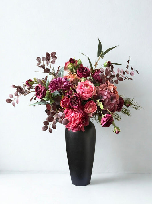 Bouquet of artificial flowers in a black vase on a white background