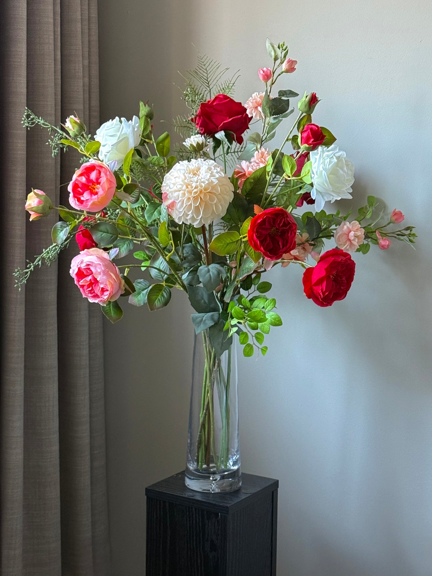 Artificial Best & Bloom Bouquet of red, white, and pink flowers in a clear vase against a neutral wall.