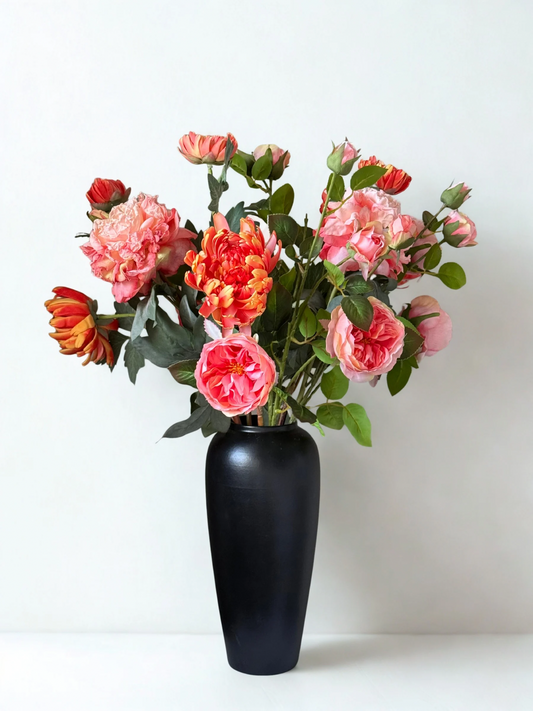 Black vase with pink and orange flowers on a white background