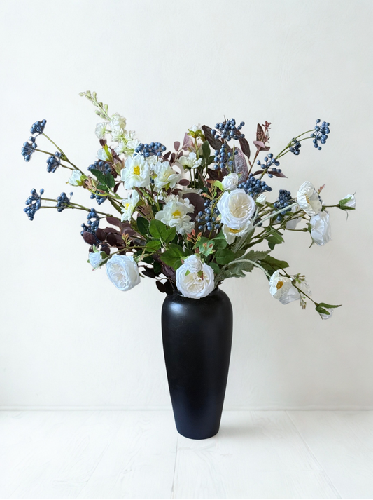 Black vase with a bouquet of white and blue flowers on a white background
