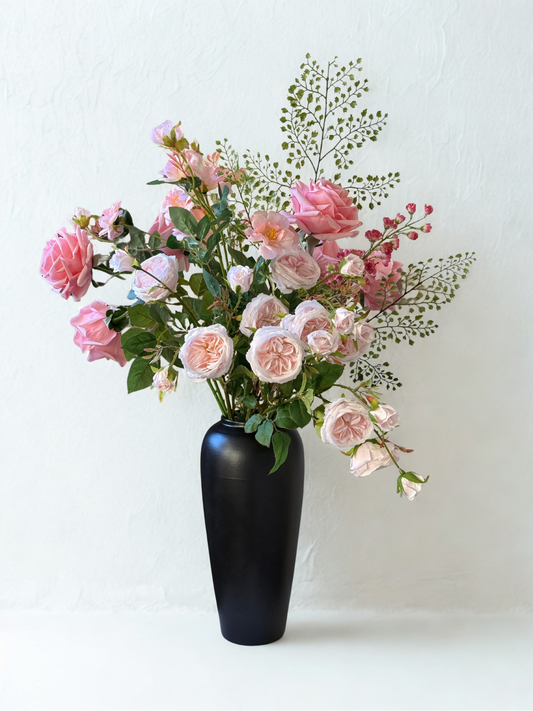 Bouquet of pink flowers in a black vase on a white background