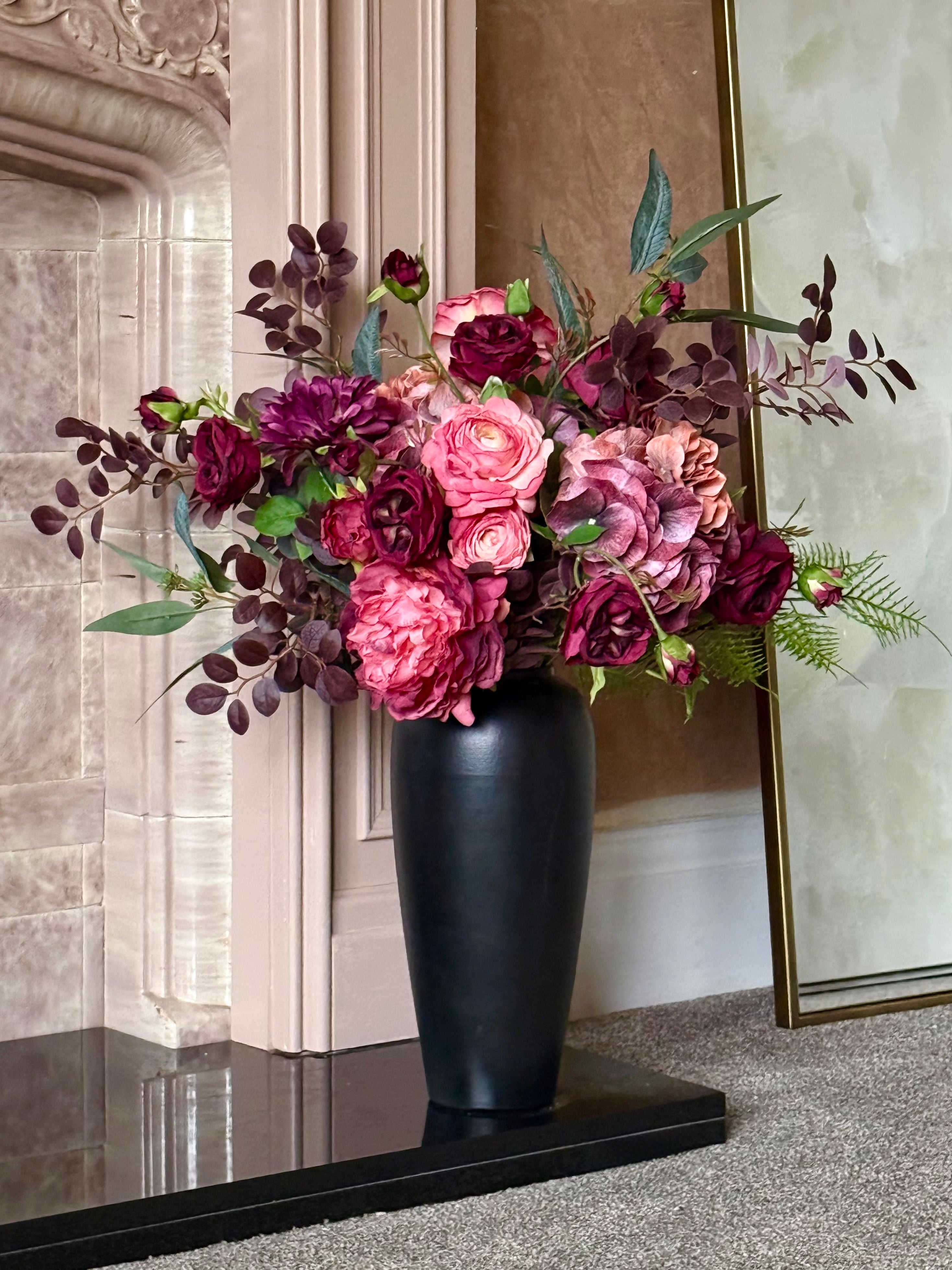 Artificial Floral arrangement in a black vase against a 1930s tiled fireplace