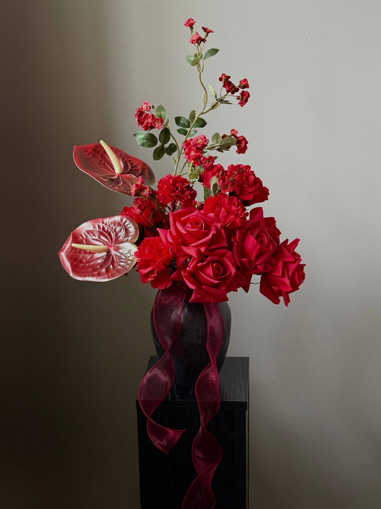 Best & Bloom Realistic Artificial Flowers Vase with red flowers and ribbons on a dark surface against a gray background