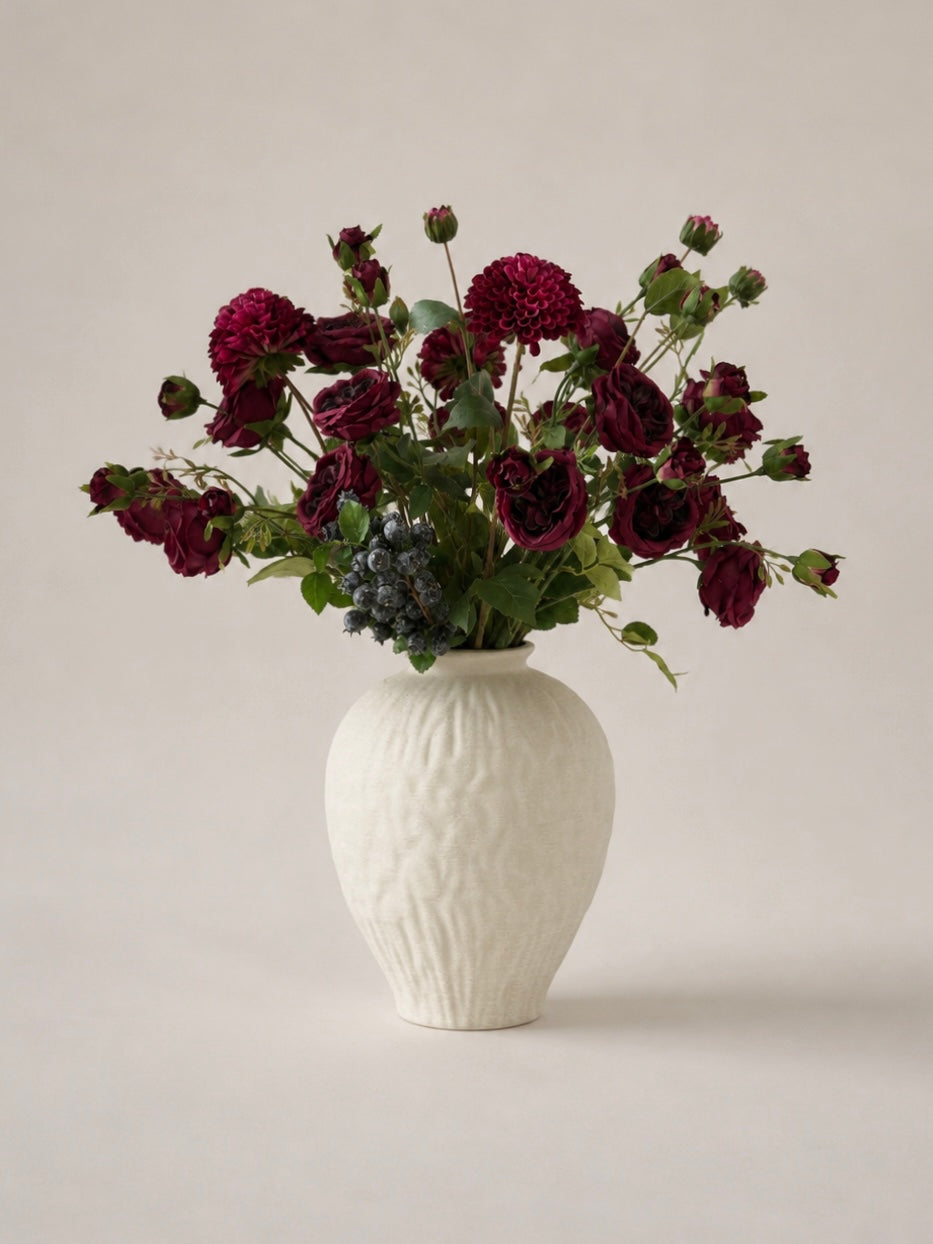 White textured vase with dark red flowers on a light background