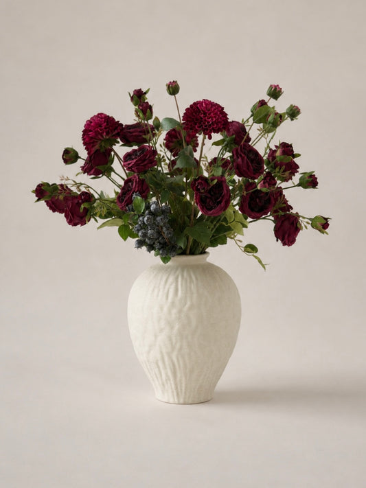 White textured vase with dark red flowers on a light background