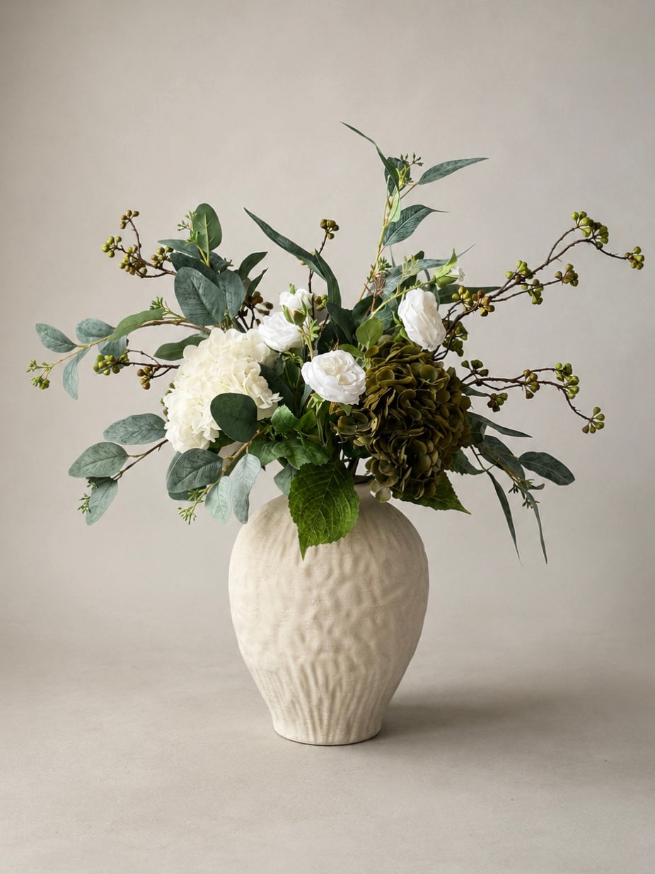 Floral arrangement in a textured white ceramic  vase on a neutral background