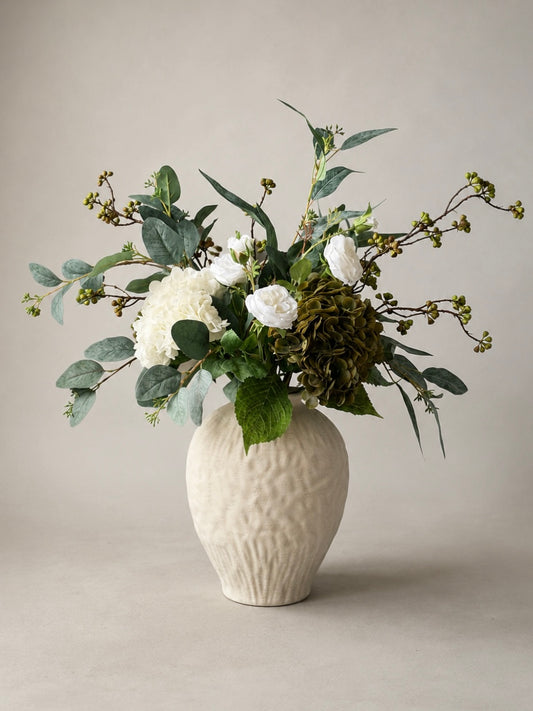Floral arrangement in a textured white ceramic  vase on a neutral background