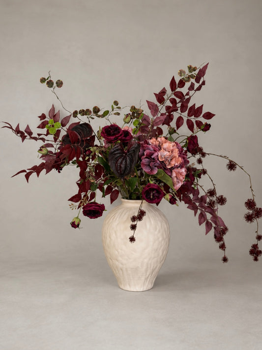 Vase with a bouquet of burgundy flowers on a plain background