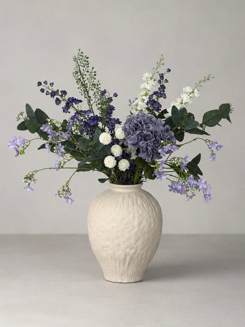 White vase with a bouquet of flowers on a gray background