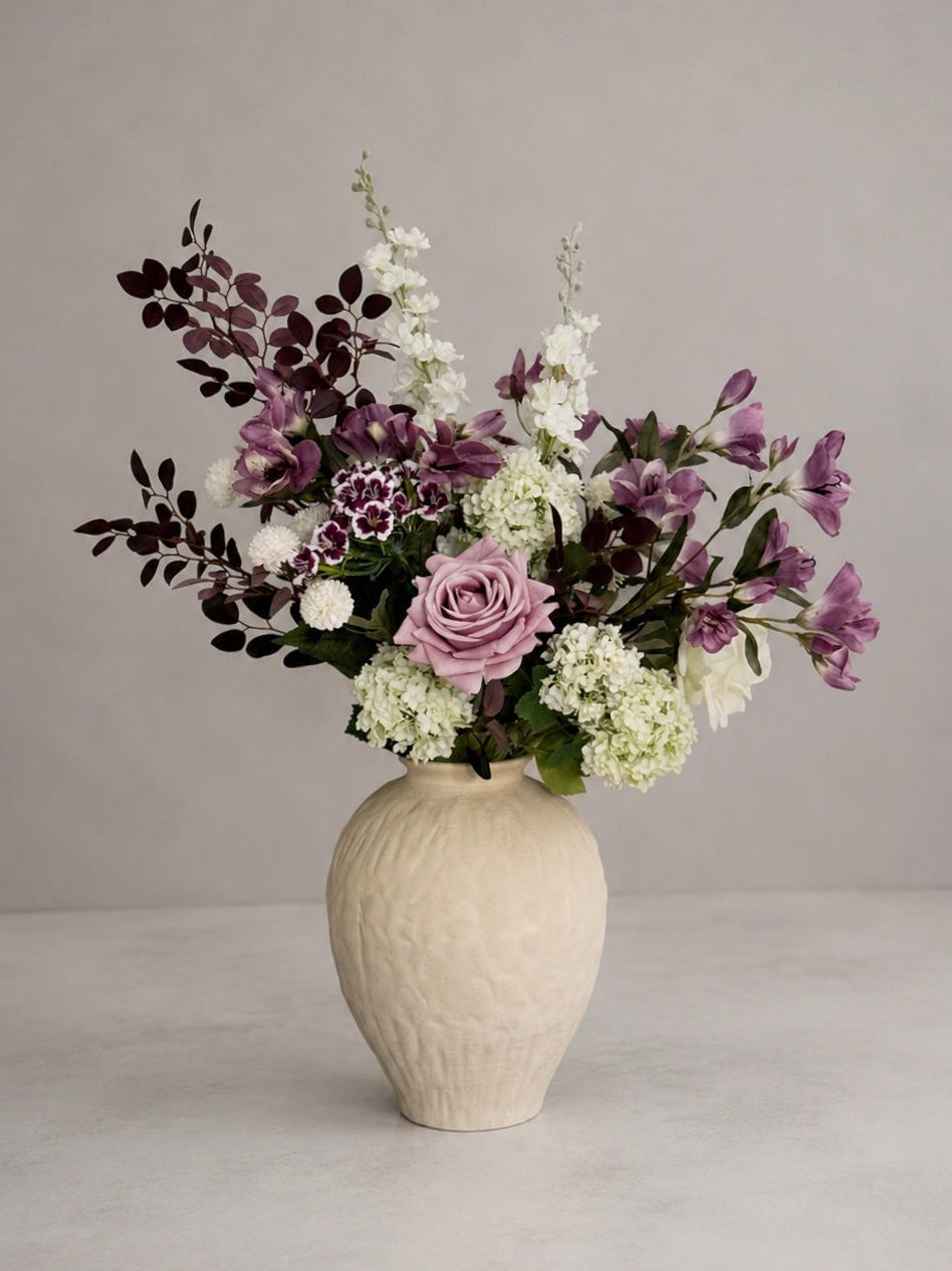 purple sweet william Floral arrangement in a textured vase on a neutral background