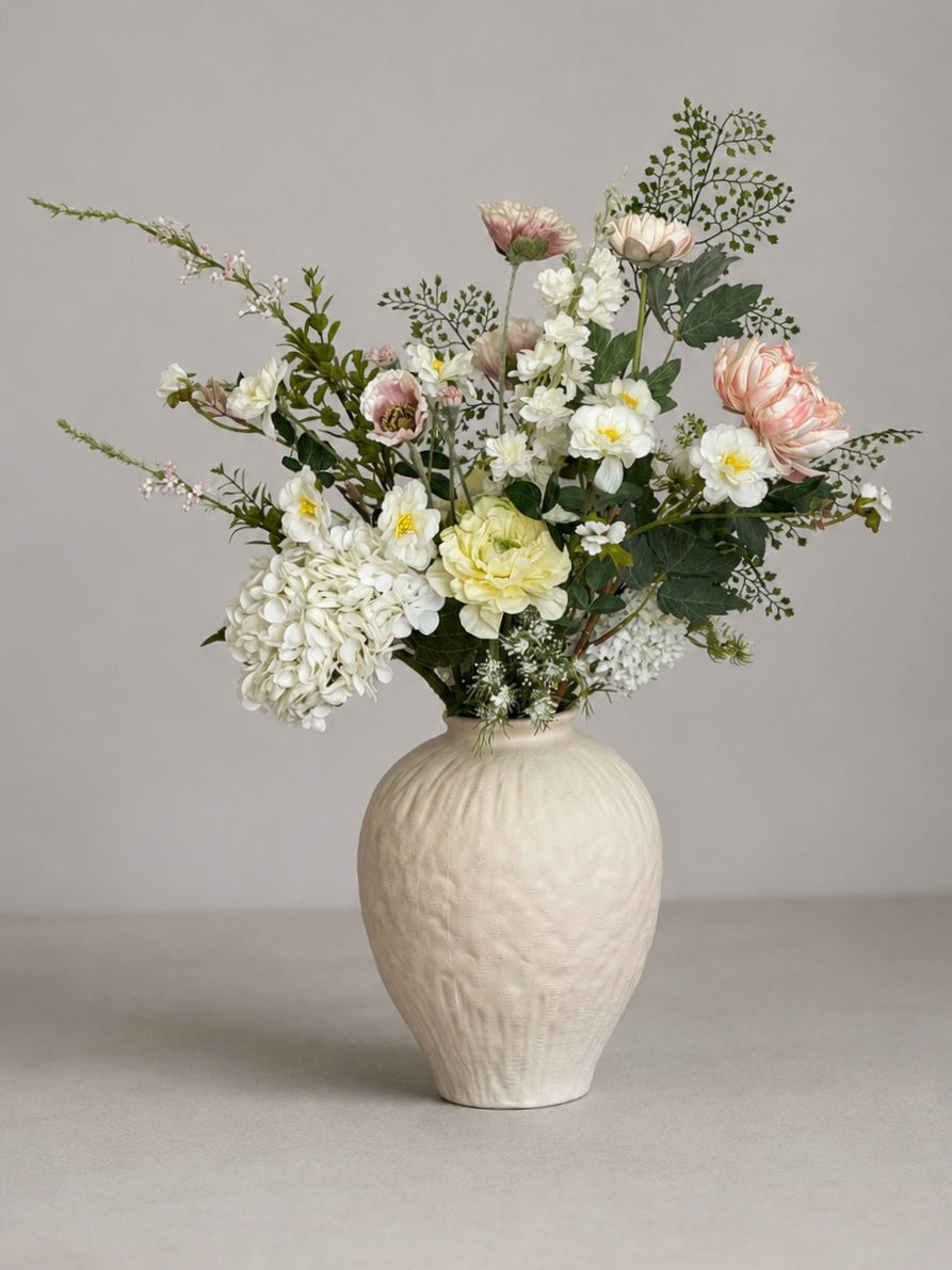 Floral arrangement in a textured vase on a neutral background
