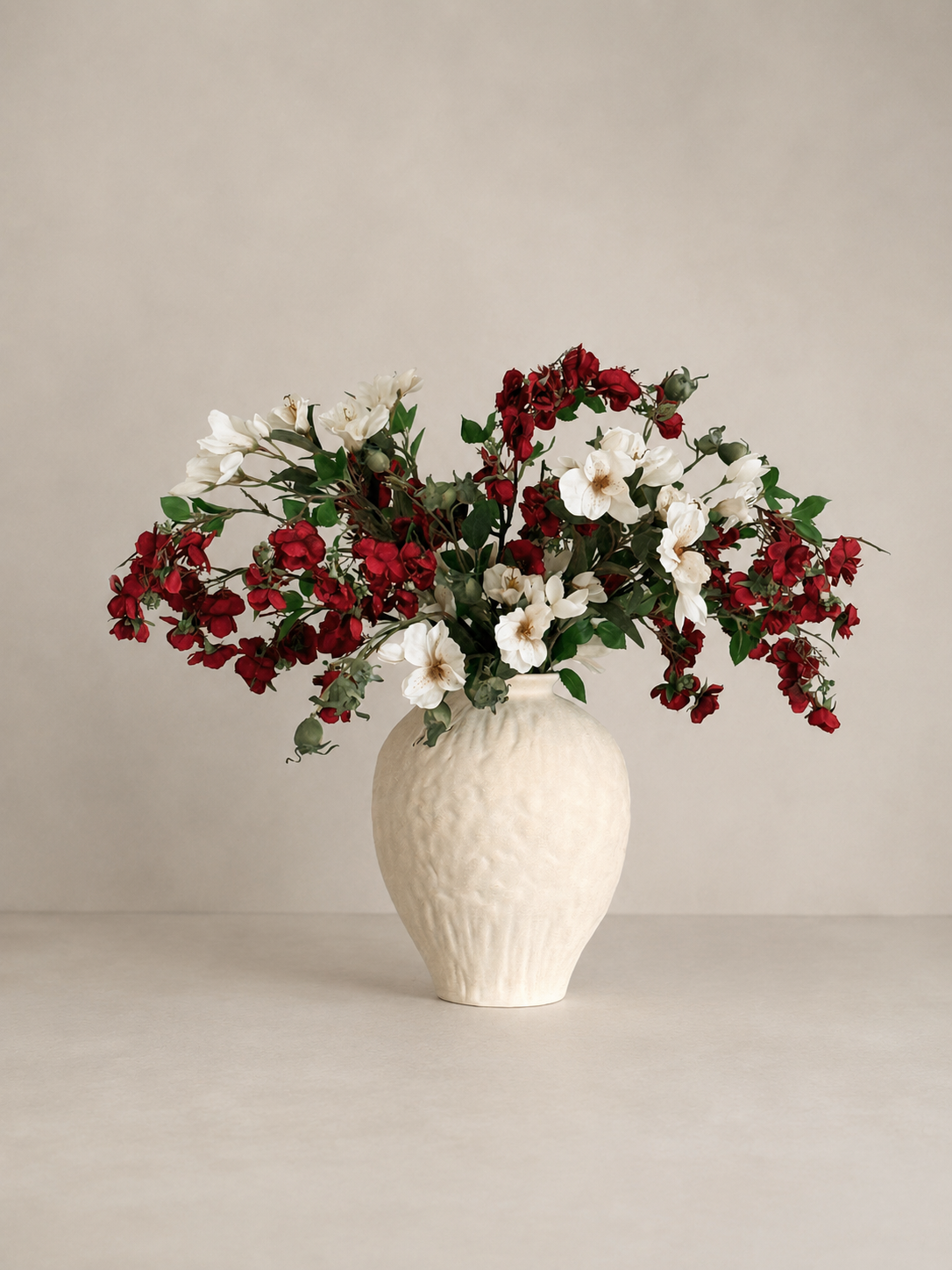 White vase with red and white flowers on a beige background